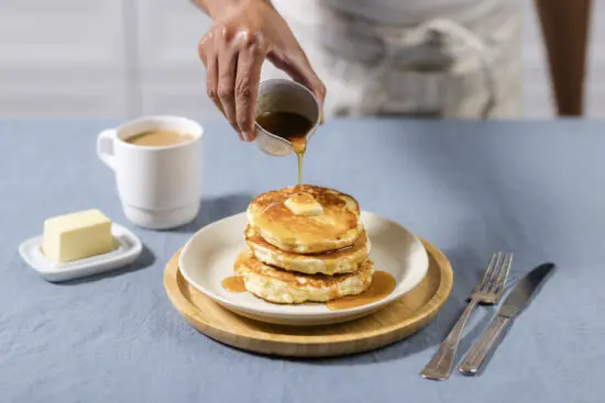 stack of pancakes with a side of butter and coffee