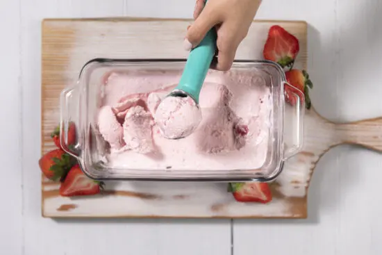 scooping strawberry cottage cheese ice cream from glass container